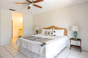 A hotel room with a bed, two bedside tables, a ceiling fan, and a door leading to another room. - 3bd/2ba Amazing Villa 10min->disney (Kissimmee)