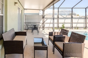 A covered outdoor seating area with wicker furniture and a view of a swimming pool. - 3bd/2ba Amazing Villa 10min->disney (Kissimmee)