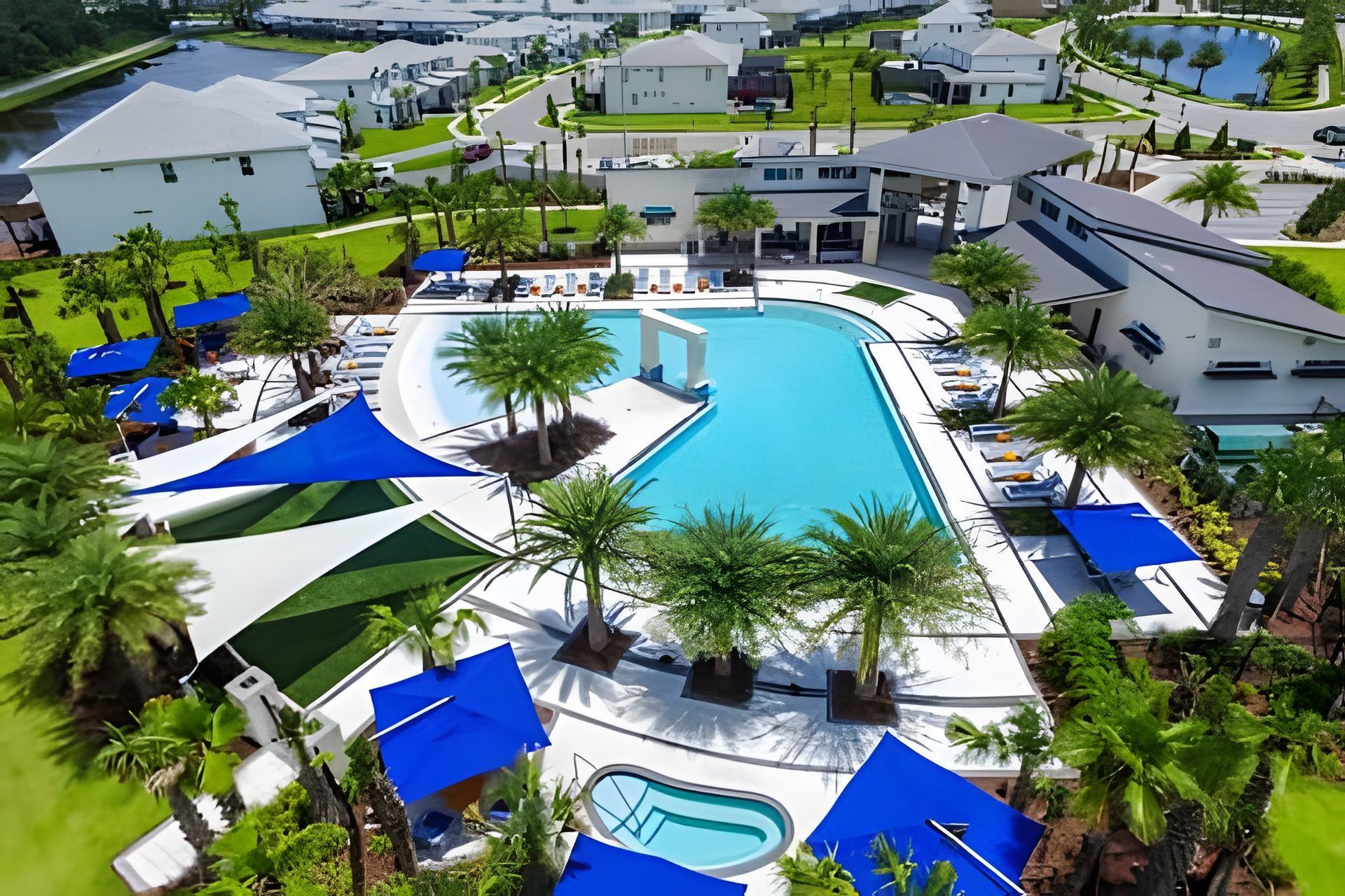 A resort with a large swimming pool, sun loungers, and palm trees.