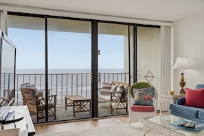 Uma varanda com vista para o mar, equipada com cadeiras e uma mesa.
