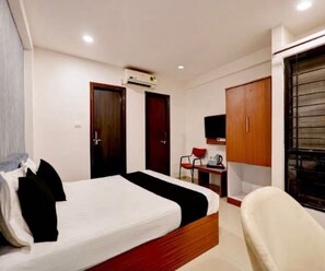 A hotel room with a bed, a desk, a chair, and a wardrobe. - Deluxe Room Hotel Expression (Indore)