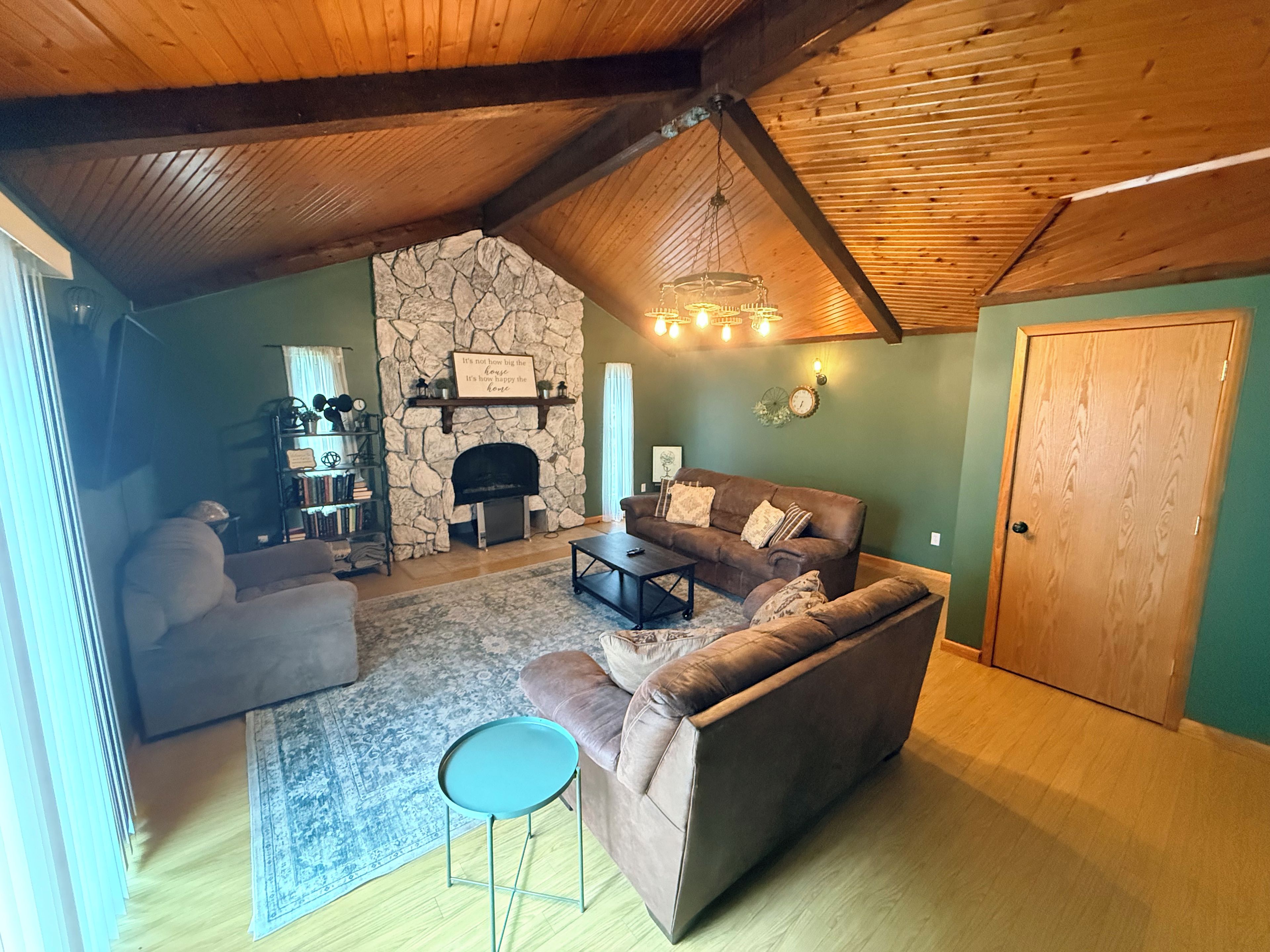 A cozy living room with a stone fireplace, a brown leather sofa, a coffee table, and a small side table.
