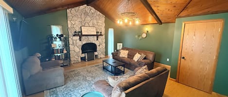 A cozy living room with a stone fireplace, a brown leather sofa, a coffee table, and a small side table.