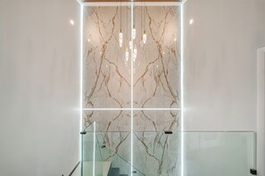 Et moderne interiør med en marmorvæg og trappe med glasgelænder.