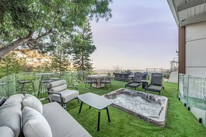 Eine Dachterrasse mit Gartenmöbeln, einem Whirlpool und Blick auf die Stadt.