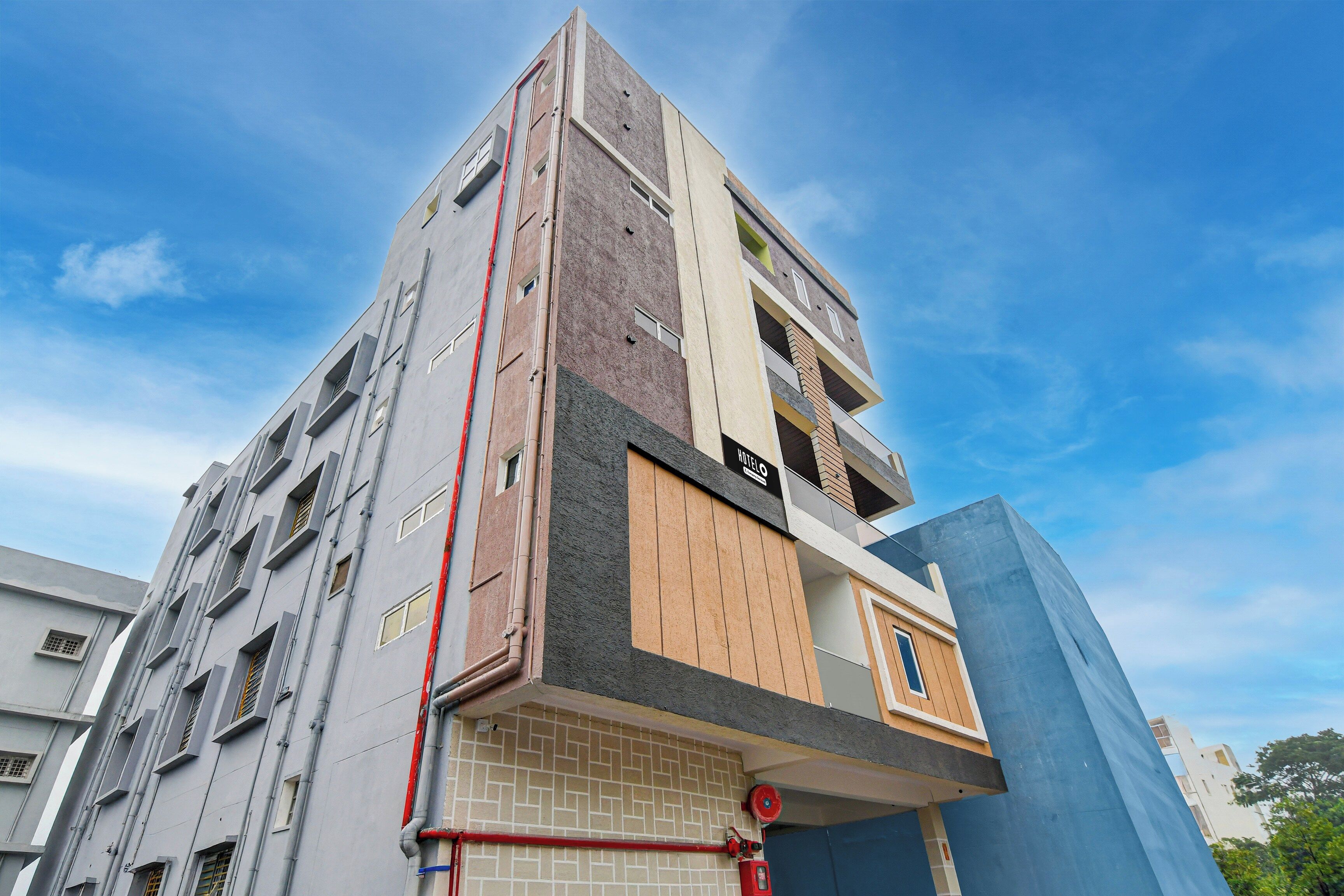 Et hotel med flere etager, moderne facade, flere balkoner og en synlig brandhane.
