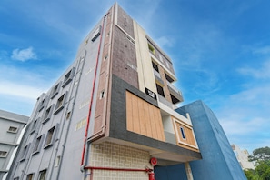 Un hotel de varios pisos con fachada moderna, múltiples balcones y un hidrante visible.