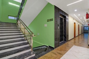 A modern interior with a staircase, a fire exit sign, and a hallway with doors.