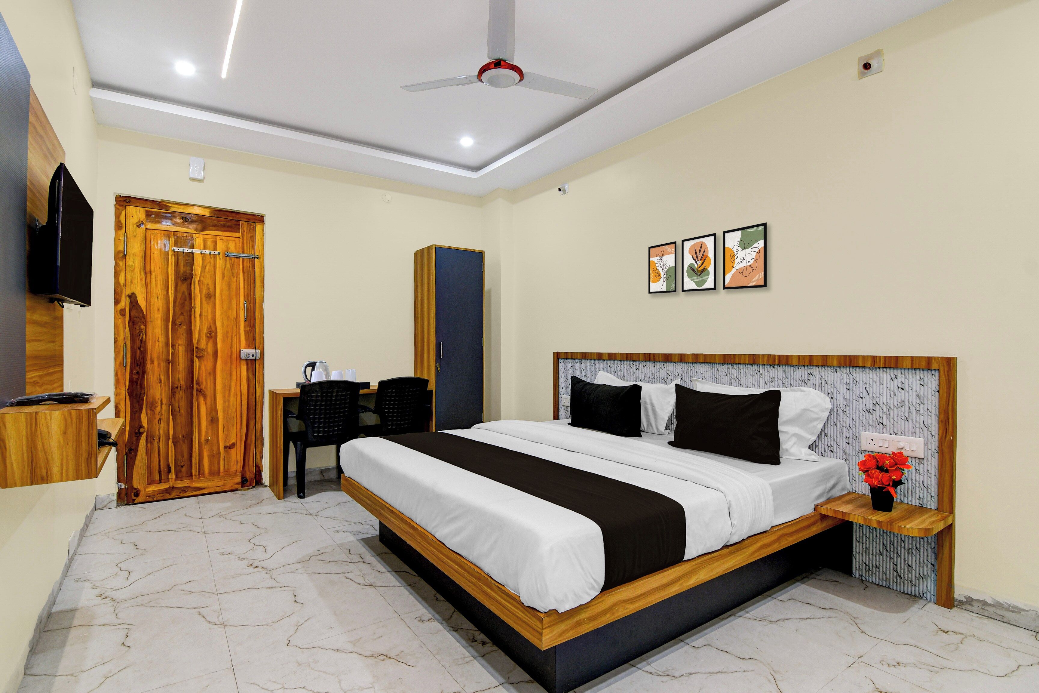 Habitación de hotel con cama, escritorio, silla, televisión y cuadros en la pared.