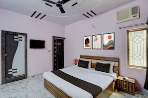 Un dormitorio con cama, ventilador de techo, televisor montado en la pared, una puerta y ventana con vistas.
