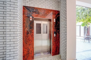 An elevator with a red and black marble finish, surrounded by white brick walls.
