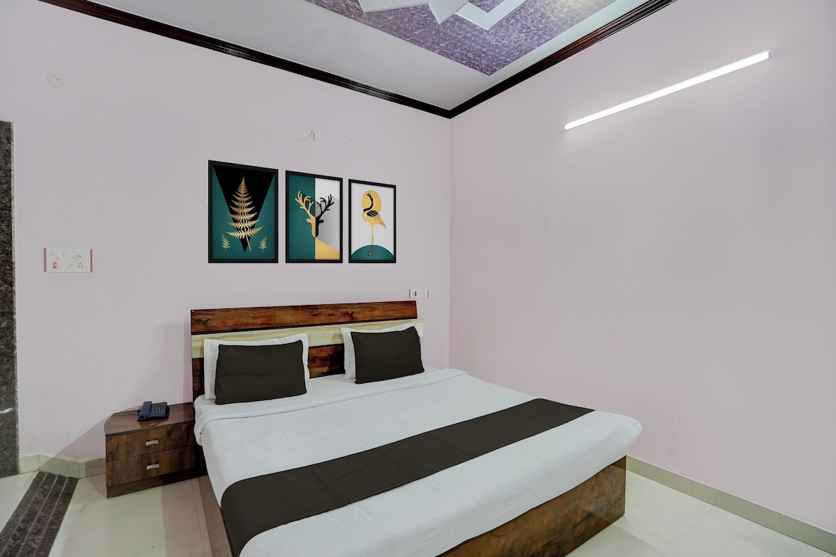 Un dormitorio con cama, mesitas de noche, cabecera y una obra de arte en la pared.