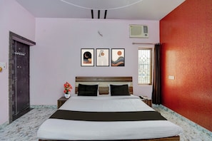 Quarto com uma cama, mesa de cabeceira, vaso de flores e três quadros na parede.