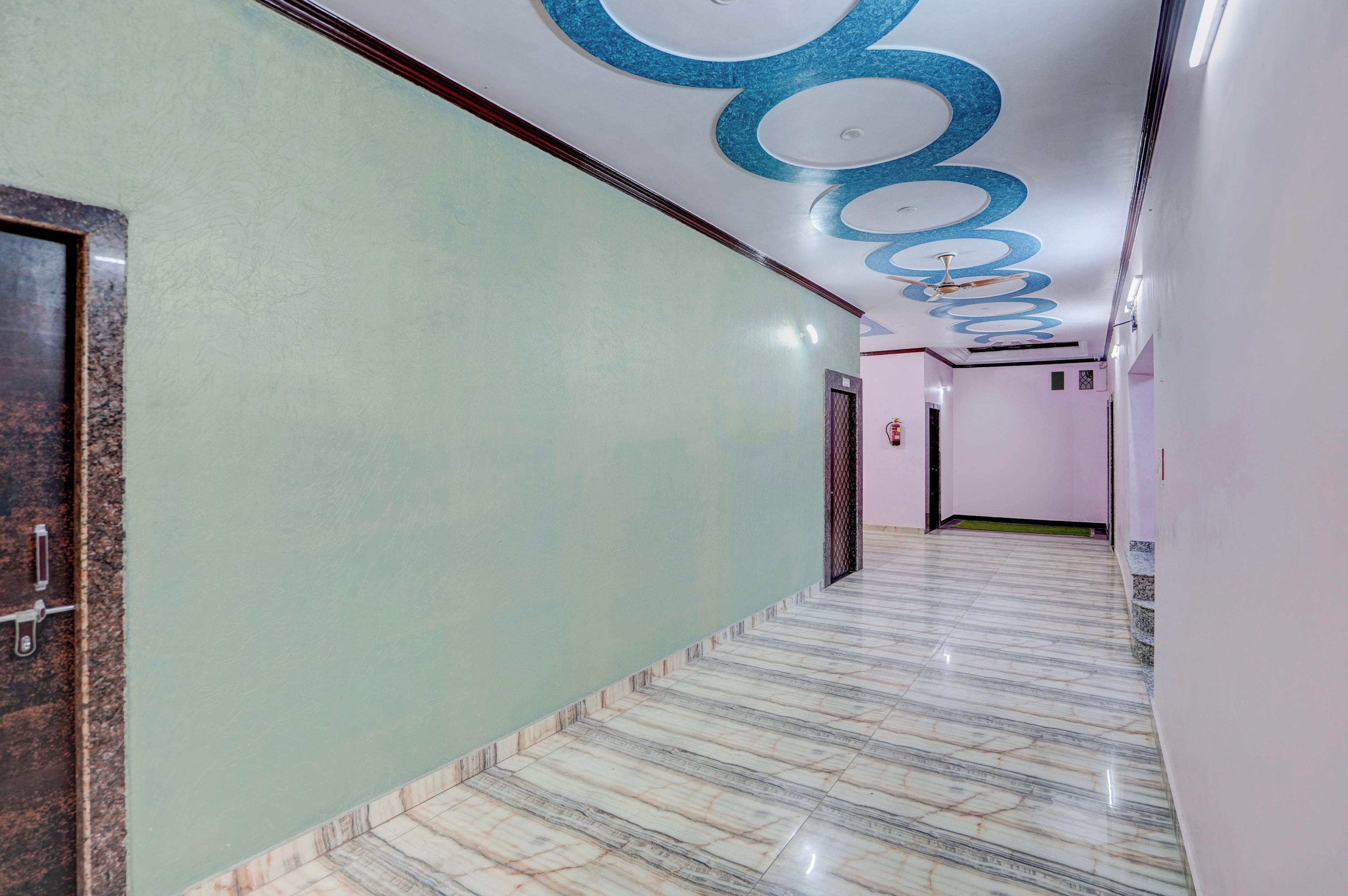 A corridor with a marble floor, a green wall, and a ceiling with a blue design.