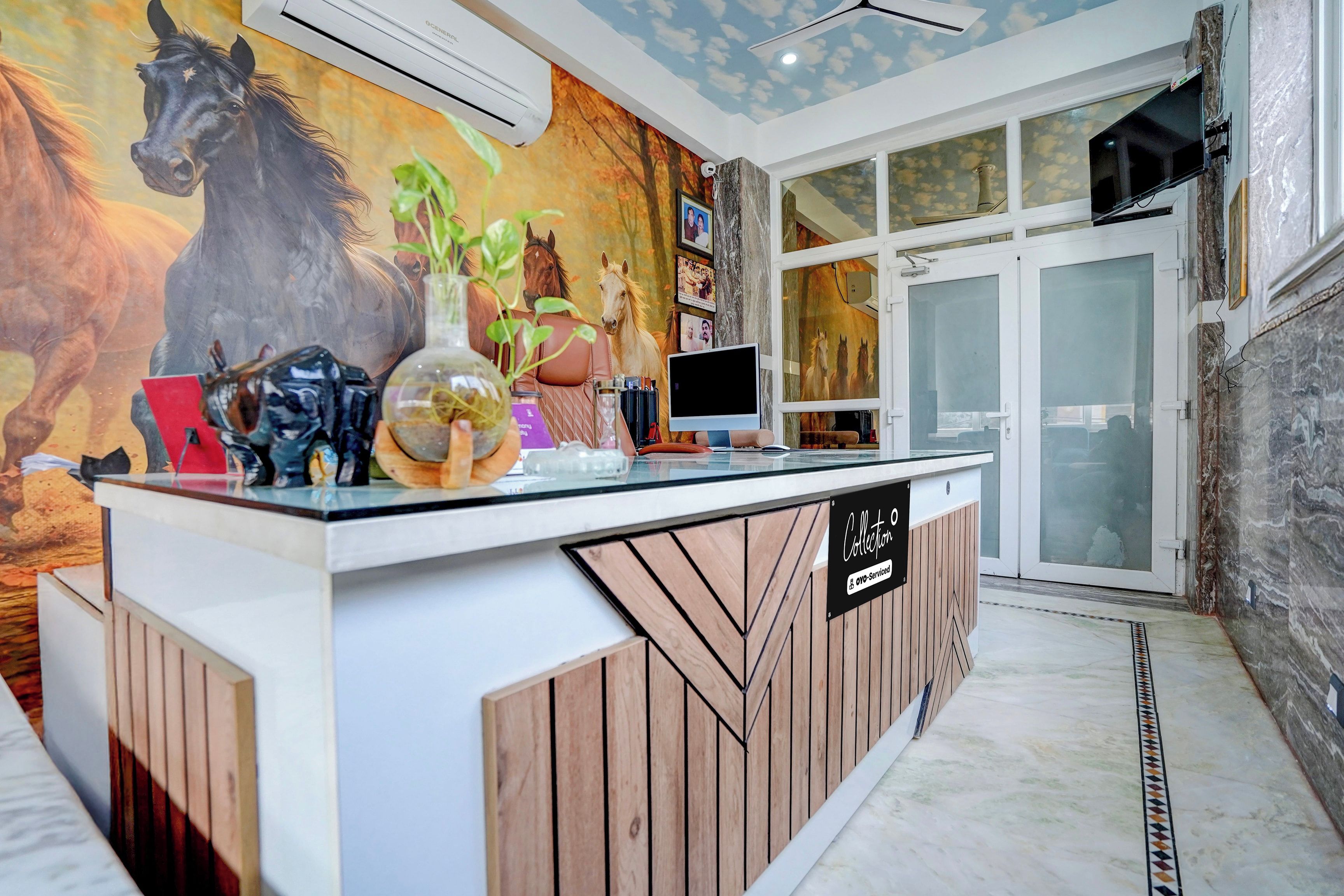 Una recepción con un mural con tema de caballos, un televisor y un letrero que dice 'Collection 5'.