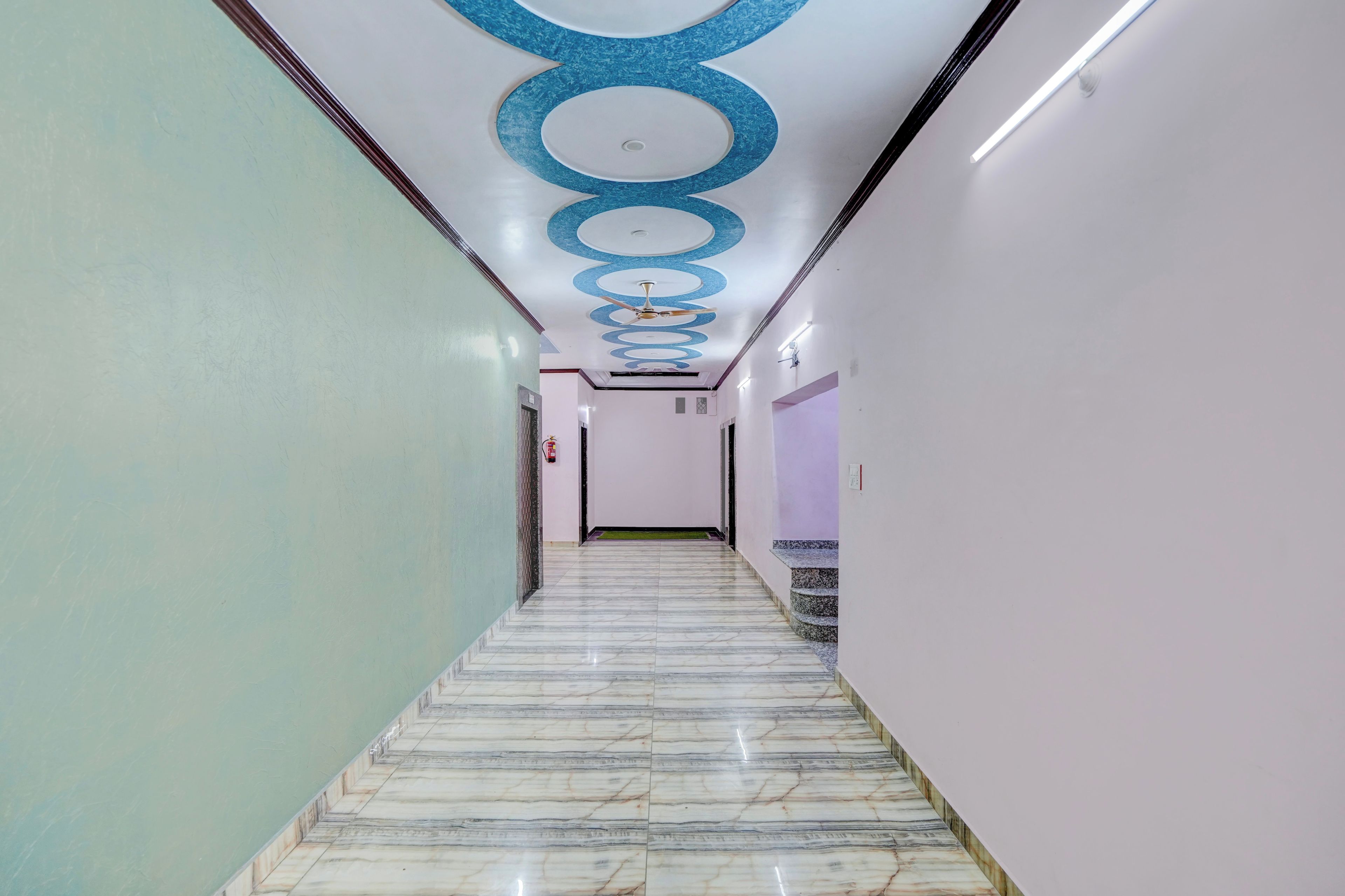 A corridor with a marble floor, white walls, and a ceiling with circular patterns.