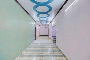 A corridor with a marble floor, white walls, and a ceiling with circular patterns.