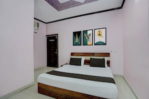 Quarto com cama, cabeceira de madeira e três quadros na parede.