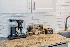 Une cuisine équipée d’une machine à café, de bocaux étiquetés « café » et « thé », et d’une boîte étiquetée « filtres ».