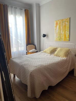 A bedroom with a bed, curtains, a chair, a floor lamp, and a painting on the wall. - New Listing (Nice)