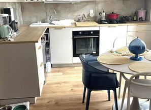 A modern kitchen with a built-in oven, a coffee maker, and a red pot on the countertop. - New Listing (Nice)