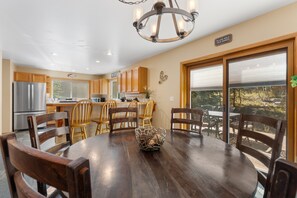 A modern kitchen with wooden cabinets, a stainless steel refrigerator, and a chandelier. - Spacious 5BR Wildernest Home | Private Hot Tub & Views (Silverthorne)