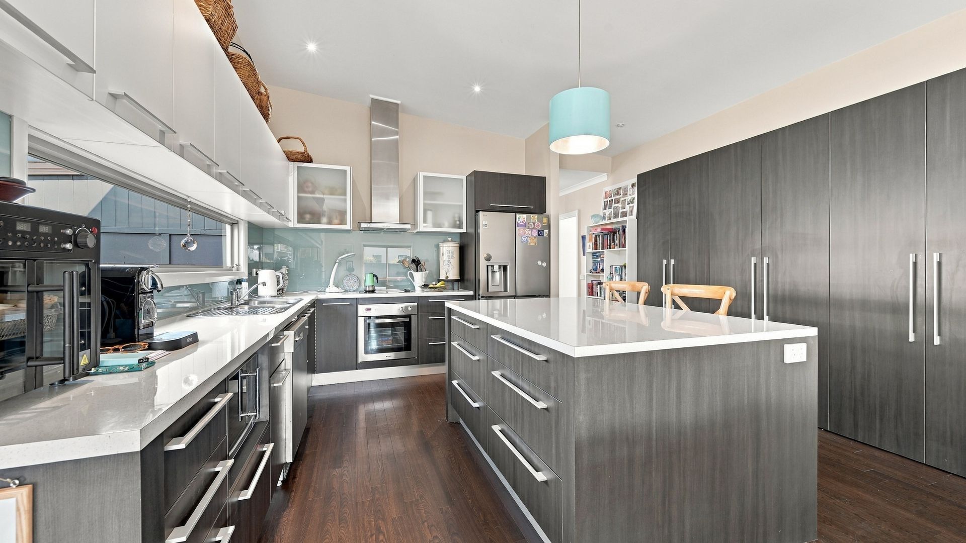 A modern kitchen with a central island, built-in appliances, and a pendant light.