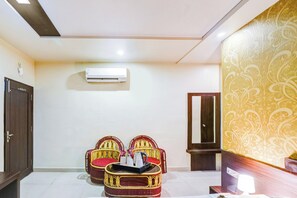 Una habitación de hotel con diseño moderno, que incluye una televisión de pantalla plana, un sofá, un muro decorativo y una puerta.