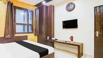 Una habitación de hotel con una cama, un escritorio con televisor de pantalla plana, un reloj en la pared y una puerta.