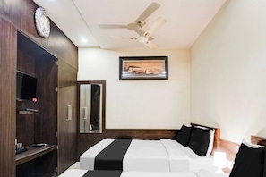 Quarto de hotel com cama, ventilador de teto, quadro e guarda-roupa.