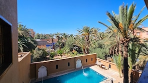 A pool with a water feature, surrounded by palm trees and a clear blue sky.