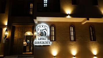 A building facade with illuminated signage for 'Layali Quarzazate Maison Photos.'