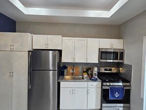 A modern kitchen with stainless steel appliances, white cabinets, and a tiled backsplash. - The Ocean Whisper's Escape @Jett's Place (Mt. Thompson)