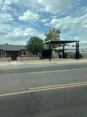 Un estacionamiento con estructura cubierta, un edificio de fachada de ladrillo y cielo despejado.