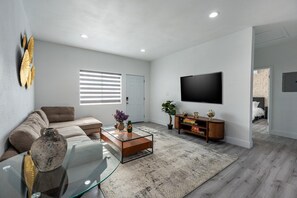 A modern living room with a sofa, coffee table, and a flat-screen TV mounted on the wall.