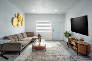 A modern living room with a sectional sofa, a coffee table, a flat-screen TV, and decorative wall art. - anaheim 2 bedroom guest house (Anaheim)