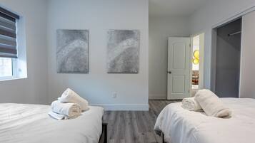 Quarto de hotel com duas camas, uma porta e duas obras de arte penduradas na parede.