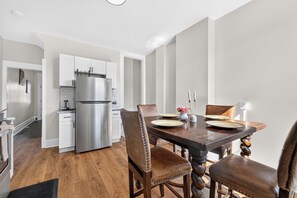 Eine moderne Küche mit weißen Schränken, einem Edelstahlkühlschrank und einem Essbereich mit Holztisch und Ledersesseln.