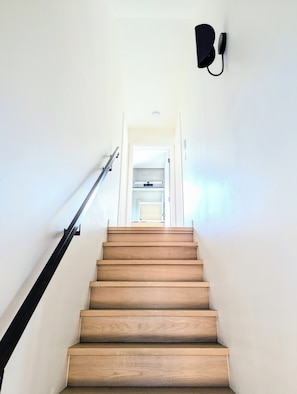 A wooden staircase with a handrail, leading to a doorway at the top. - Downtown Kelowna Carriage House | Private Hot Tub, Firepit & Fenced Yard (Kelowna)