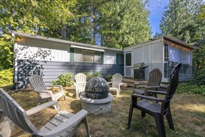 Un jardin avec un espace aménagé pour se détendre en plein air, un barbecue et un foyer.