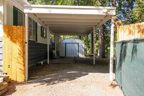 Ein überdachter Außenbereich mit einem Kiesweg, der zu einem Gerätehaus führt.