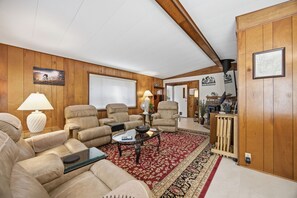 Ein Wohnzimmer mit Ledersofas, einem Couchtisch und einem roten Teppich mit Muster.