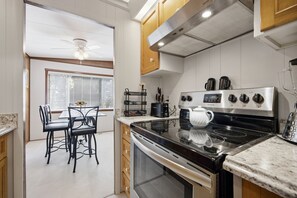Eine moderne Küche mit einem schwarzen Herd, einem Frigidaire-Kühlschrank und einem Fenster mit Jalousien.