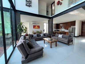 A spacious living area with a large sofa set, a coffee table, and a kitchen in the background. - 4-king size beds bedroom- house in peaceful Sayulita walk to the beach (Sayulita)