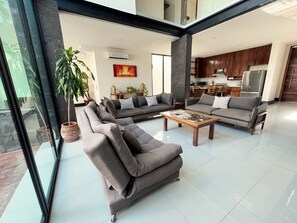 A spacious living area with a sectional sofa, a coffee table, and a potted plant. - 4-king size beds bedroom- house in peaceful Sayulita walk to the beach (Sayulita)