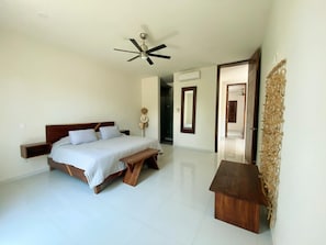 A bedroom with a bed, a bench, a ceiling fan, and a wall-mounted shelf. - 4-king size beds bedroom- house in peaceful Sayulita walk to the beach (Sayulita)