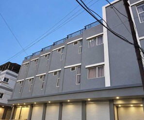 A multi-story building with a flat facade, multiple windows, and a balcony on the upper floor. - Deluxe Room Day2day Hotel (Indore)