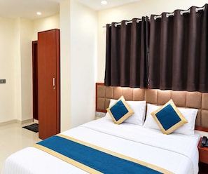A hotel room with a bed, a wooden wardrobe, and a curtain. - Deluxe Room Day2day Hotel (Indore)