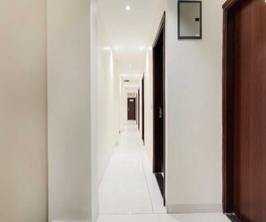 A hotel corridor with a polished floor, doors on both sides, and recessed lighting. - Deluxe Room Day2day Hotel (Indore)