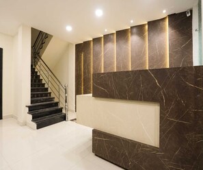 A modern interior with a staircase, a marble wall, and recessed lighting. - Deluxe Room Day2day Hotel (Indore)